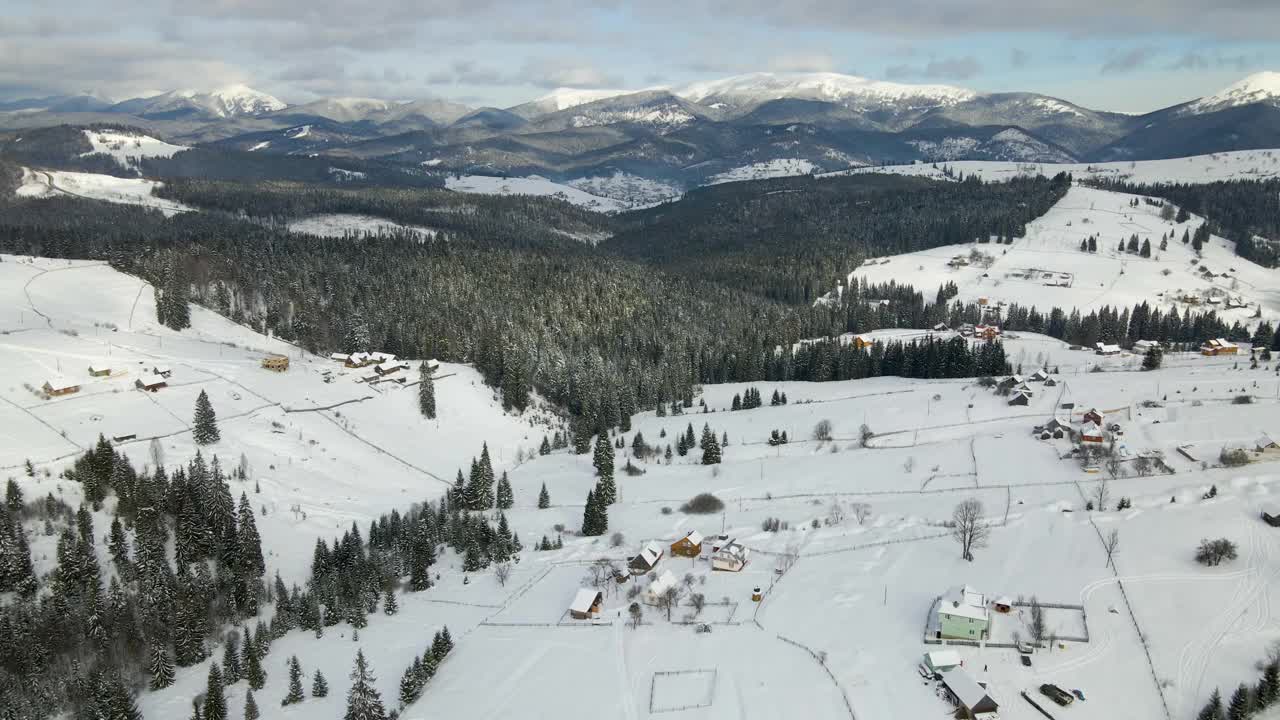 冬季景观，在寒冷的山区积雪覆盖的森林之间，偏远定居点的小乡村房屋视频素材