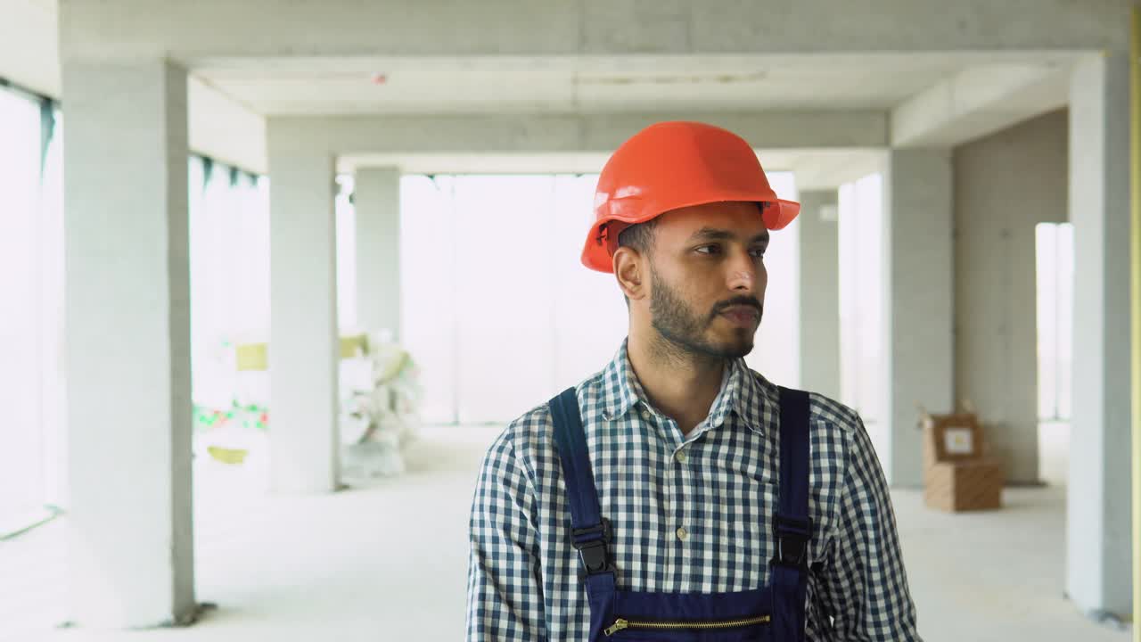 穿着制服和头盔的印度亚裔建筑工程师在办公中心的施工现场行走视频素材