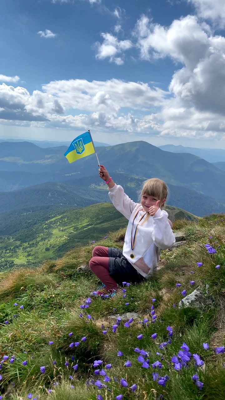 小可爱的女孩游客与乌克兰国旗在喀尔巴阡山山顶视频素材