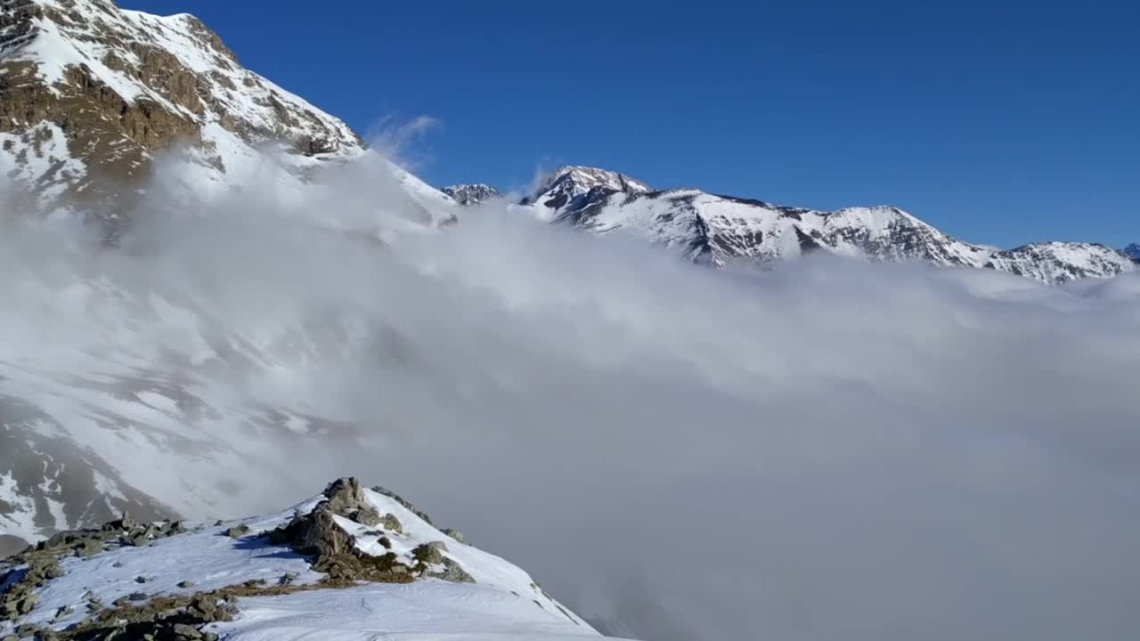 雪谷和云海在阳光明媚的山天全景:28秒视频视频素材