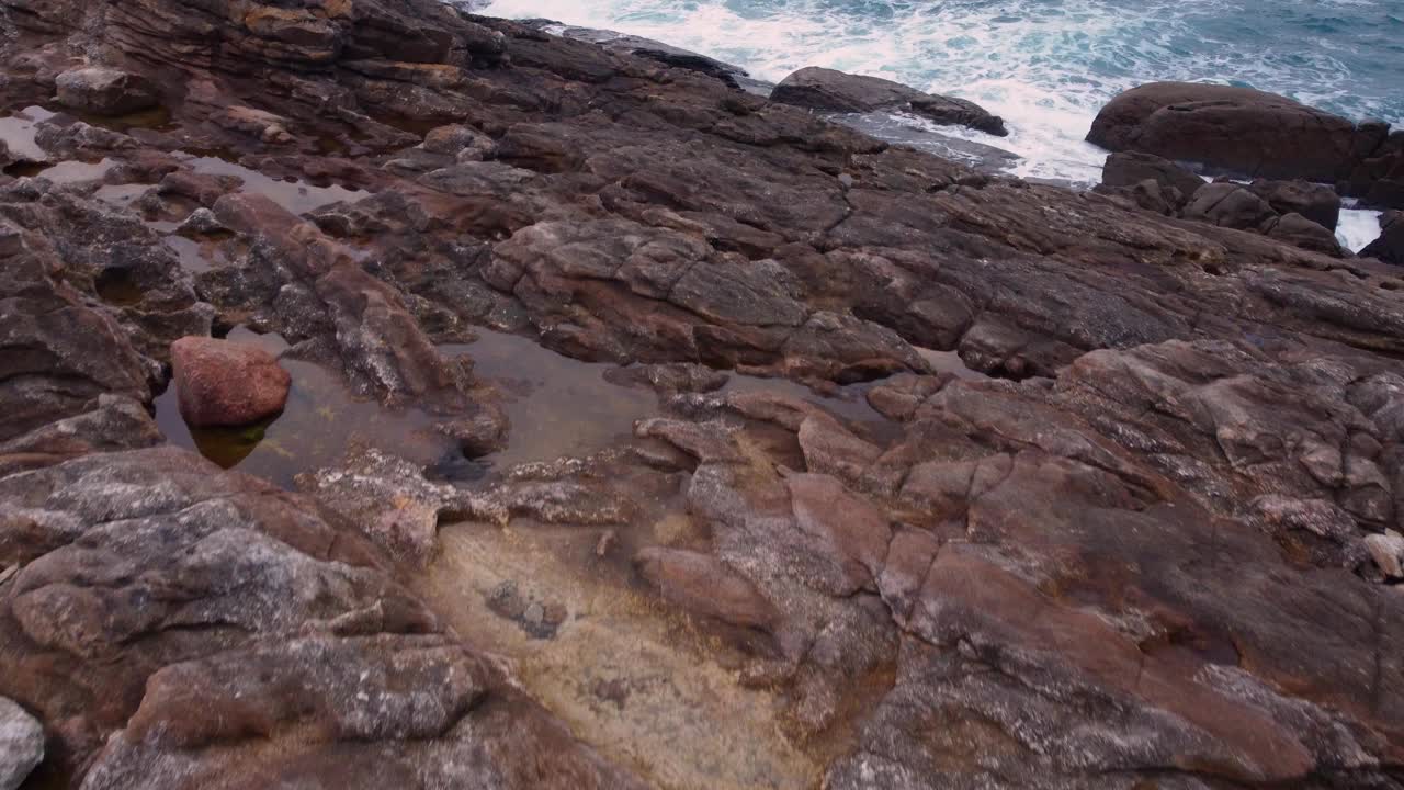 岩石海岸与泡沫海浪撞击。空中视频素材