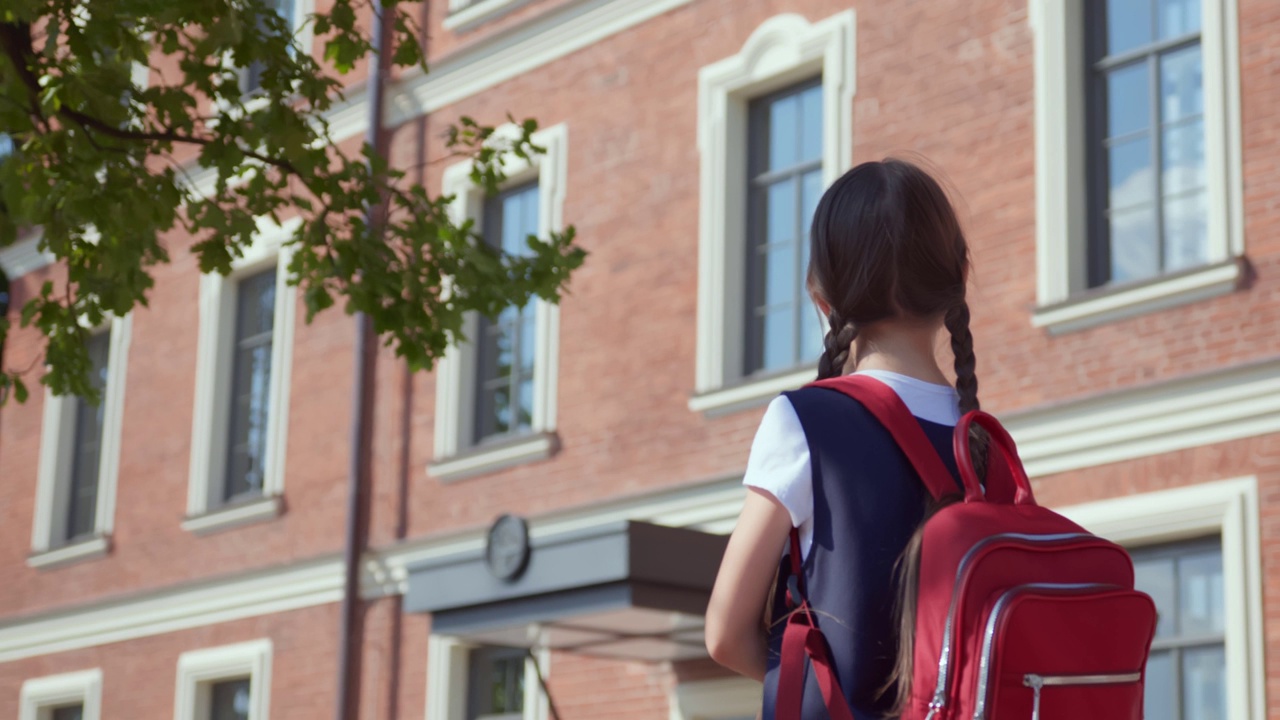 后视图的青春期前的女学生书包站在户外。视频素材