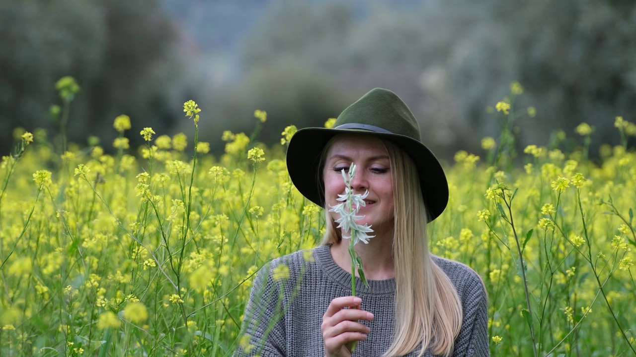 美丽的金发女人闻到春天的花朵视频素材