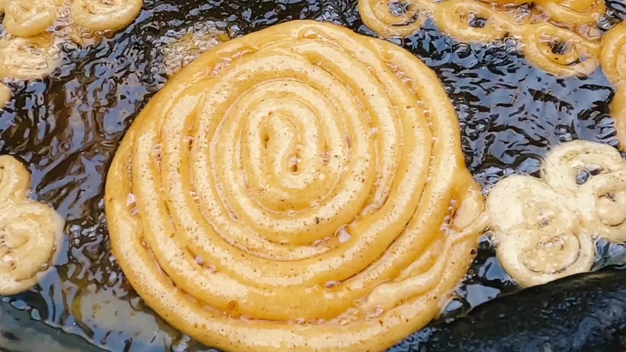 大jilebi或jilapi甜沙漠制作印度街头小吃。新鲜印度甜点Jalebi。甜贾勒比制作在深热油油炸视频下载