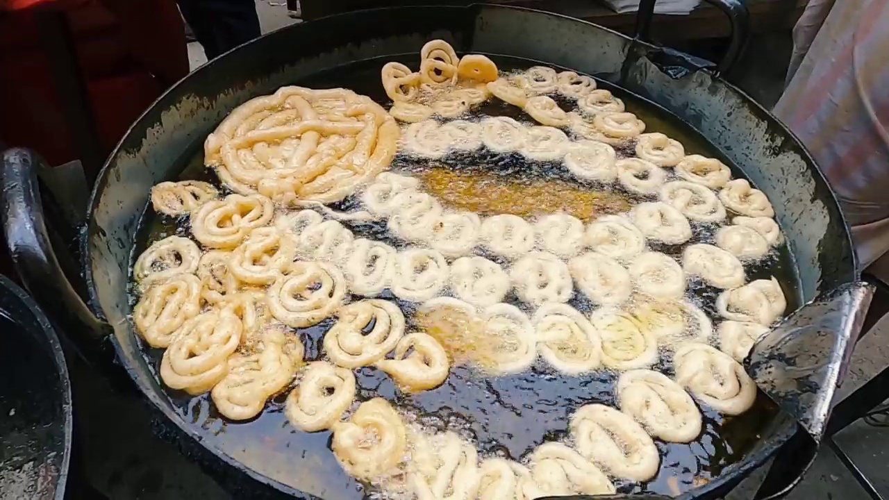 新鲜印度甜点Jalebi。甜贾勒比制作在深热油油炸视频下载