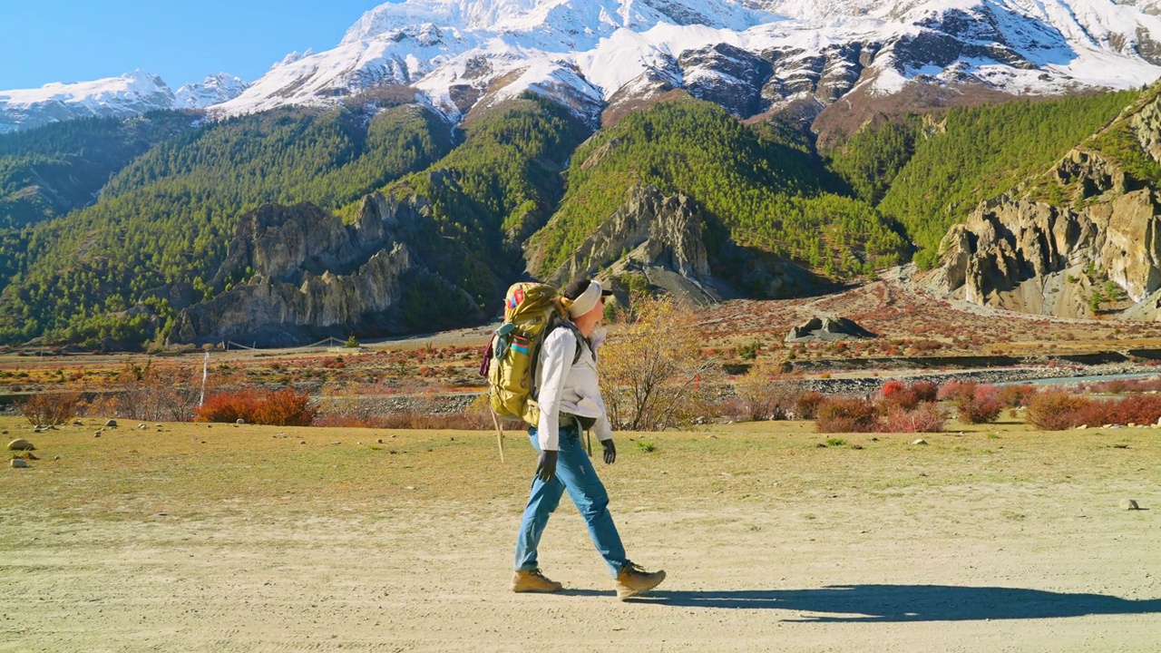 成年徒步旅行者的全身侧视图，行走在积雪覆盖的安纳普尔纳山脉的小路上，尼泊尔视频素材