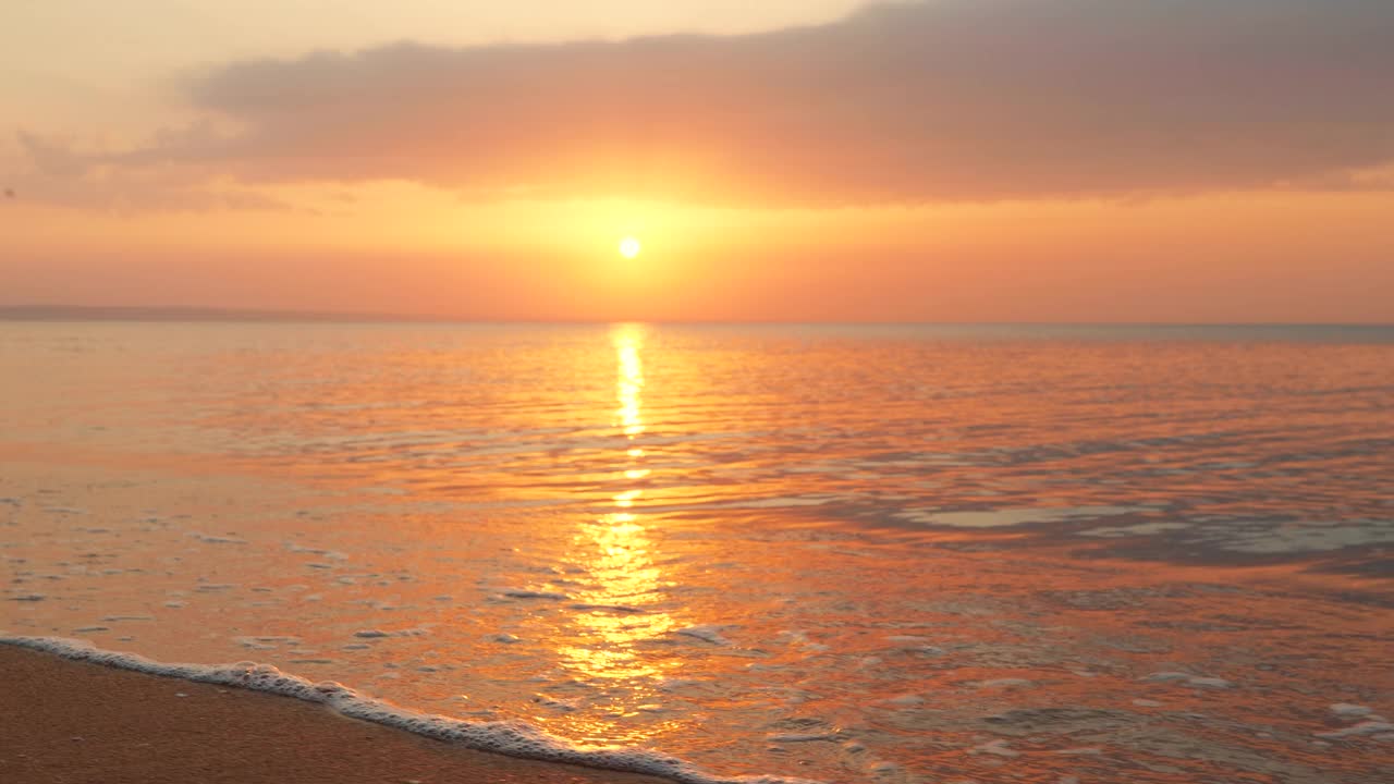 美丽的海面上有日出滑动的金色小波浪。大圆盘的太阳升起海面，阳光路径通过水。大海全景的金光。放松。自由视频素材