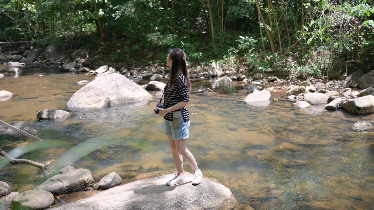 旅行者GEN -Z背包客站在河里得到了最好的照片视频素材