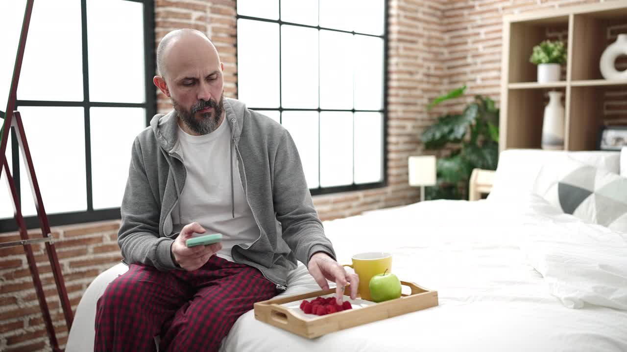 年轻的秃头男子做照片早餐坐在床上在卧室视频素材