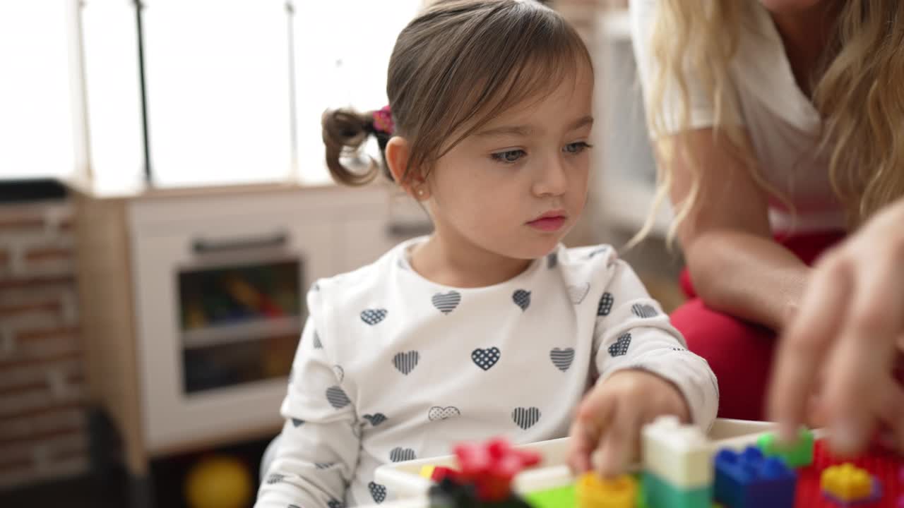 幼儿园里，老师和幼儿坐在桌子上玩积木视频素材