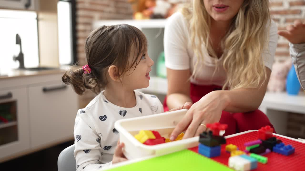 幼儿园里，老师和幼儿坐在桌子上玩积木视频素材