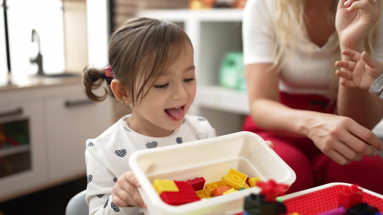 幼儿园里，老师和幼儿坐在桌子上玩积木视频素材