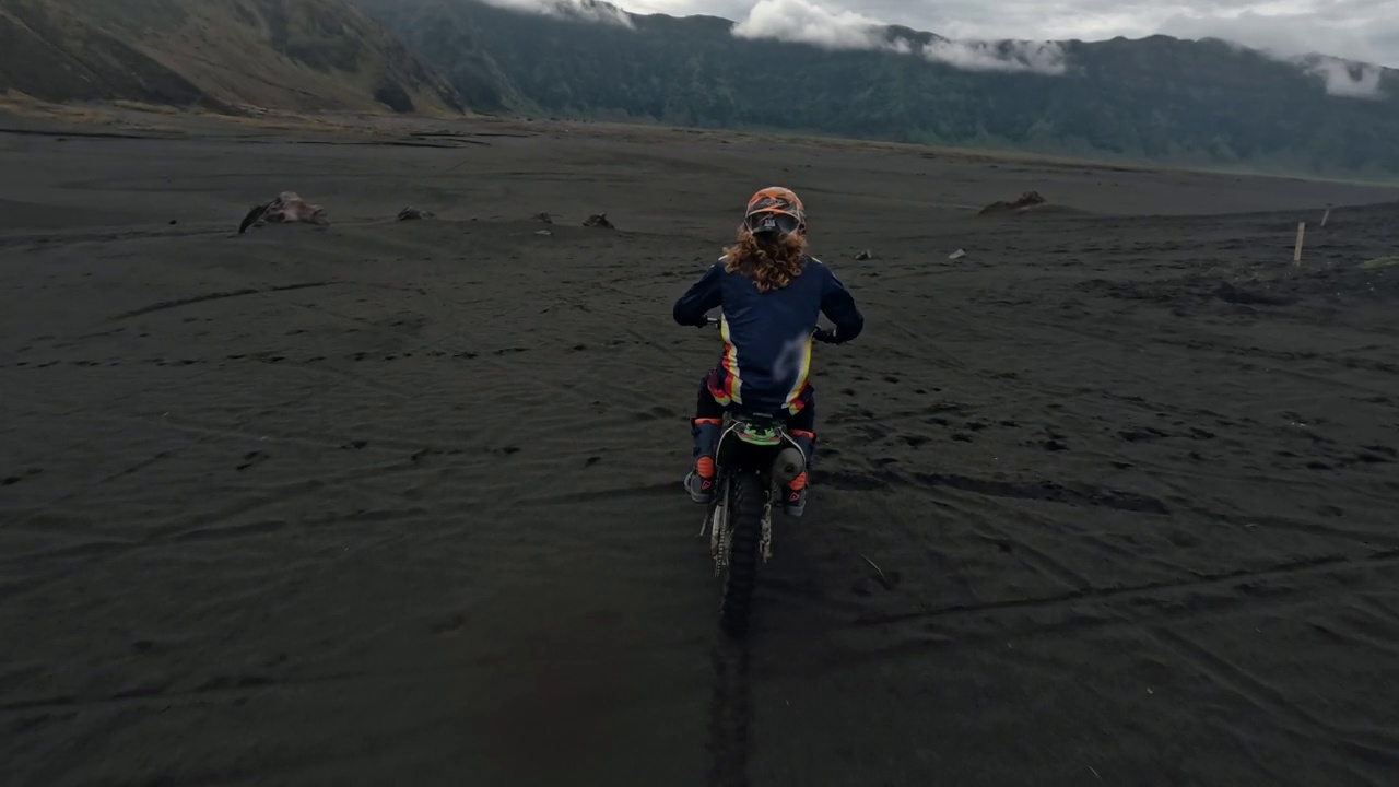 女子骑土车Enduro速度骑在熔岩场附近的火山摩托车极限运动鸟瞰图视频素材