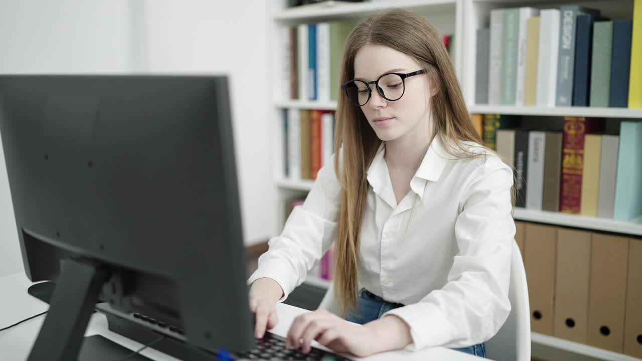 年轻的金发女学生使用电脑在大学教室学习视频素材