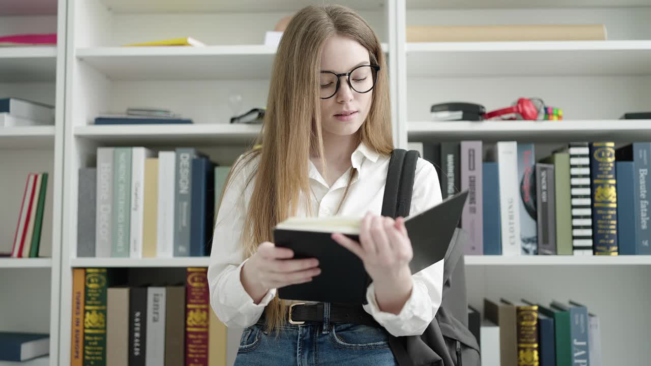 年轻的金发女学生站在大学教室里看书视频素材