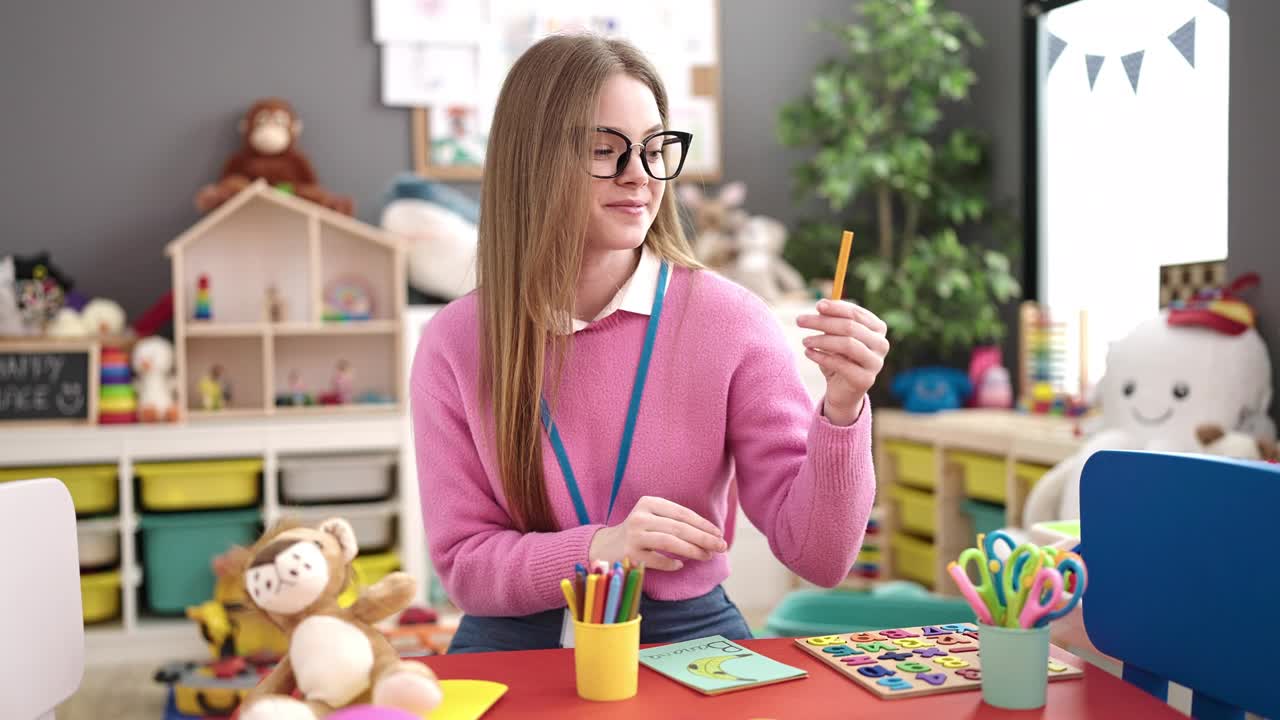 年轻的金发女人在幼儿园教书视频素材