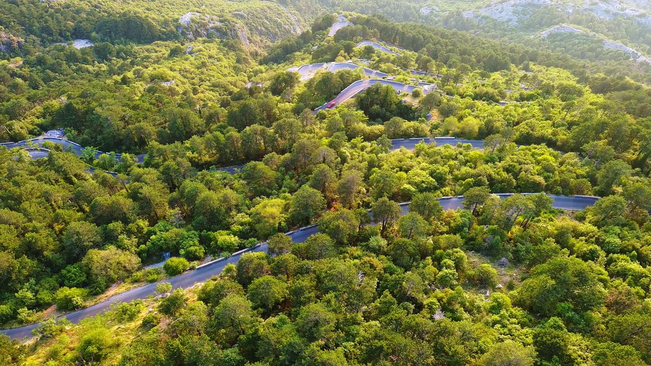 蜿蜒的道路-洛夫琴斯基蜿蜒的危险转弯，通往蒙的内哥罗山脉的顶部覆盖着植被视频素材