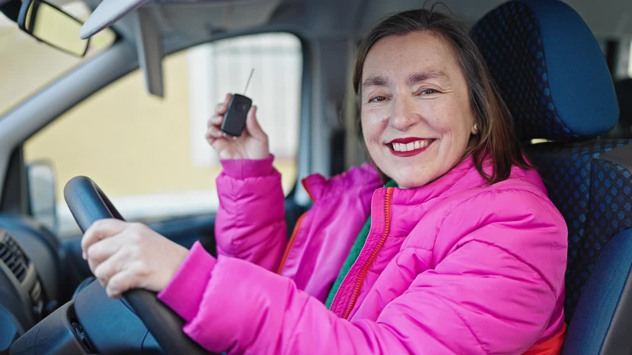 成熟的西班牙女人与灰色的头发微笑自信地在街上拿着新车的钥匙视频素材