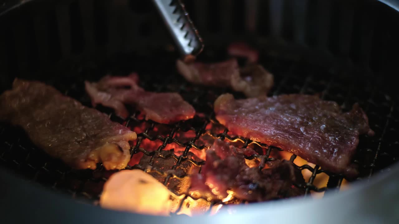 极近距离在餐厅的木炭烤架上烤生牛肉片，日式烧肉烧烤食物视频素材