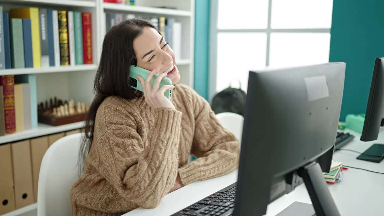 年轻美丽的西班牙女学生在大学教室里用智能手机讲电脑视频素材