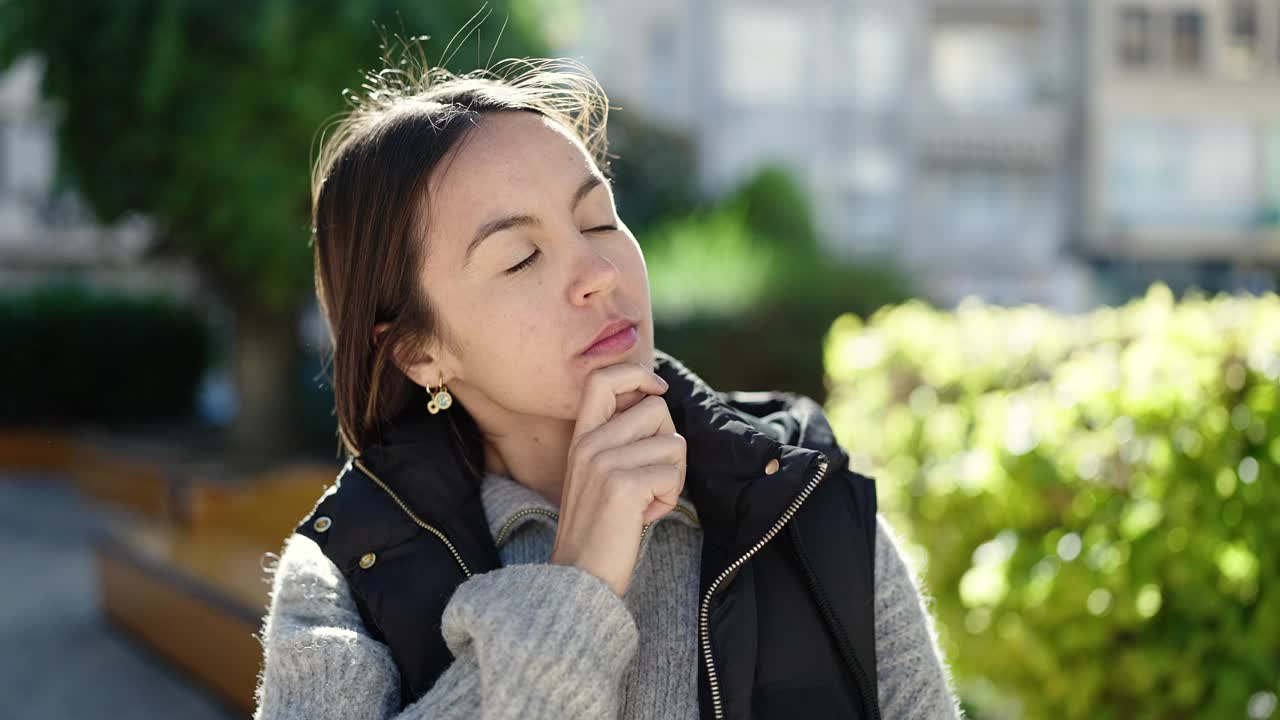 年轻美丽的西班牙女子站在公园怀疑的表情视频素材