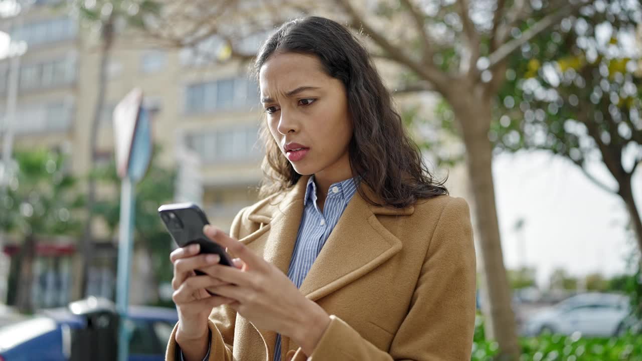 年轻美丽的西班牙女子在公园用智能手机严肃的脸视频素材