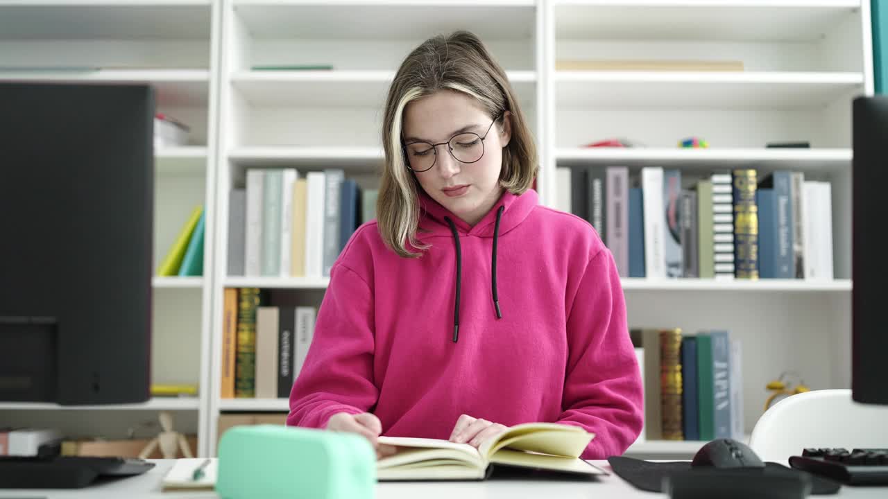 年轻的金发女学生在图书馆大学读书做沉默的手势视频素材