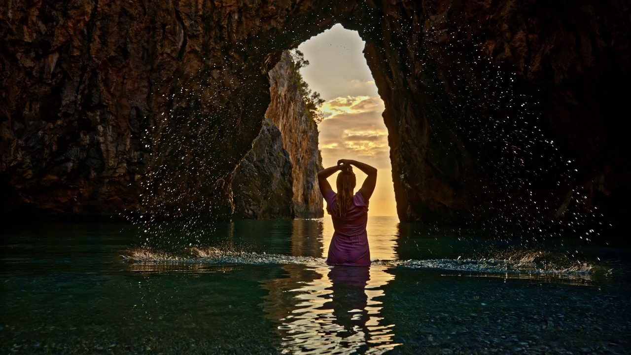 快乐的女人在美丽的拱门前在海上泼水在Spiaggia dell'Arcomagno。有吸引力的视频视频素材