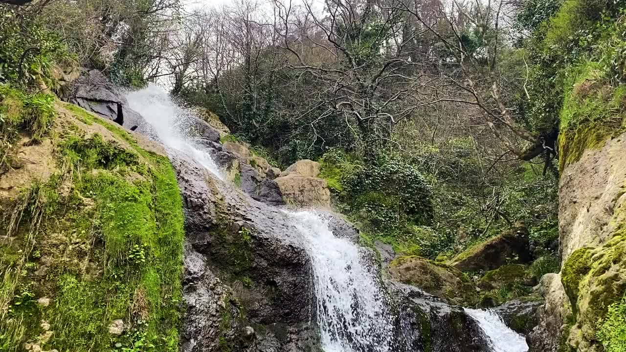 一个美丽的瀑布，在一个阳光明媚的夏日里，峡谷里有岩石、植物群和清澈的水。视频素材