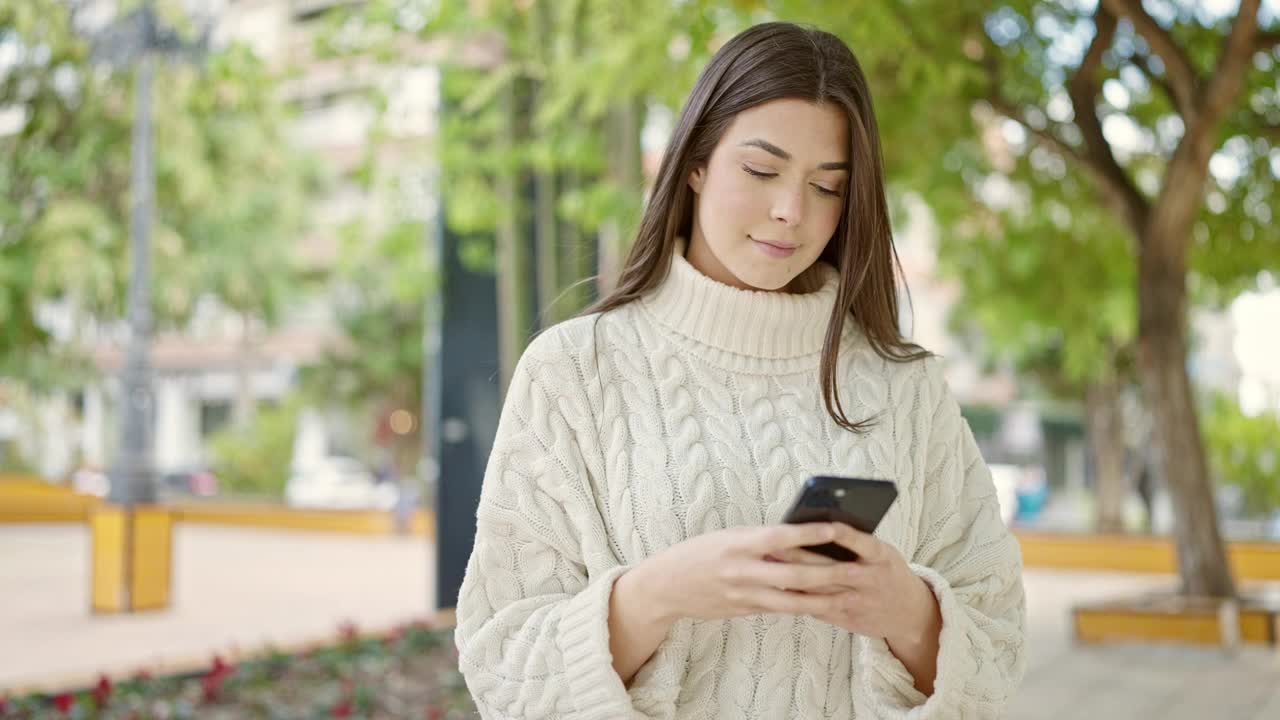 年轻美丽的西班牙女子微笑自信使用智能手机在公园视频素材