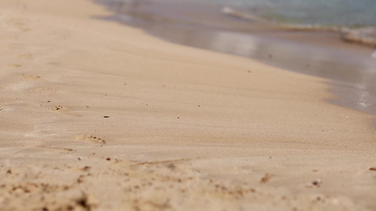 在沙滩上，女性沿着海水波浪行走。漂亮的女人走在海边冲浪。飞溅的水和泡沫。暑假视频素材