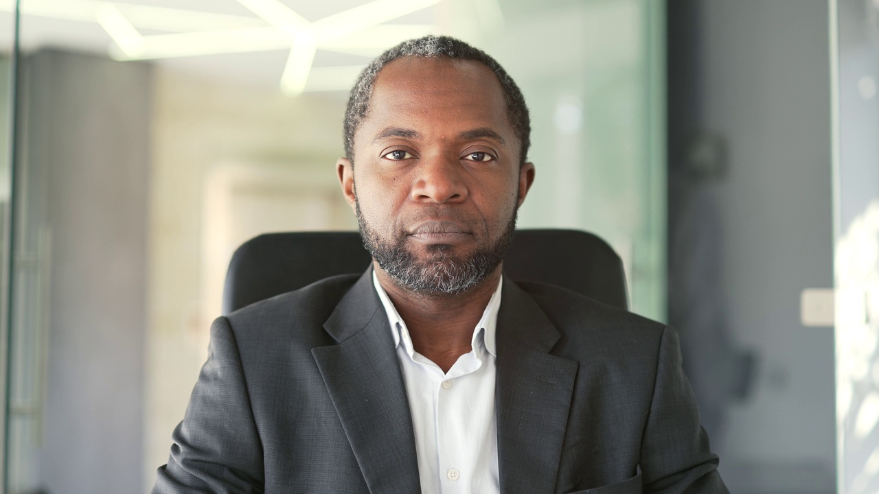 Close up portrait. Сoncentrated mature african american businessman looking at the camera while sitting at a workplace in a modern office视频素材