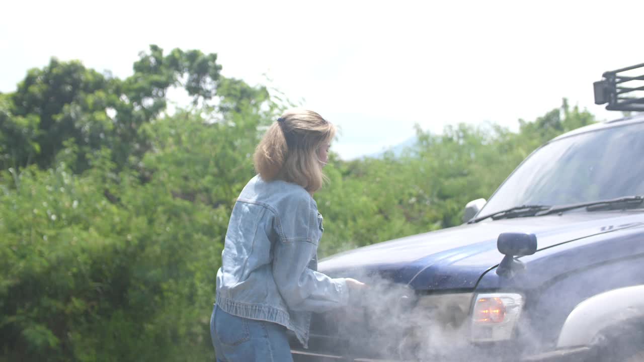 亚洲妇女汽车在路上坏了，打开汽车散热器引擎盖，看到发动机视频素材