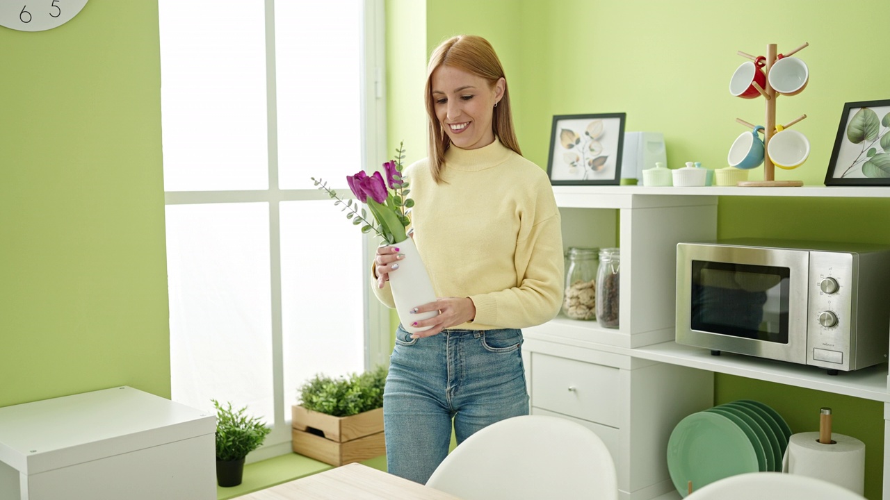 年轻的金发女人微笑着自信地在家里用鲜花装饰视频素材