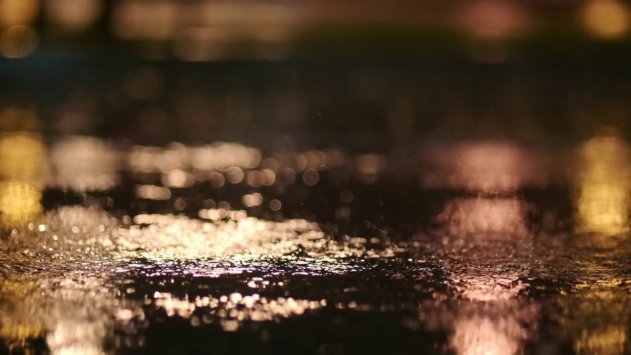 夜间城市暴雨的大气视频。大雨和汽车从低处穿过水坑时溅起的水花。视频素材