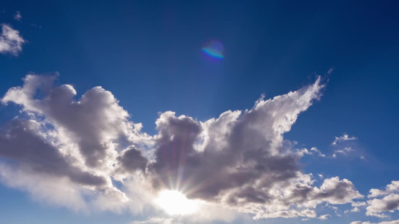 天幕云景自然背景。时光流逝的蓝天和大气中的阳光。太阳穿过蓬松的云层，在蓝天上形成美丽的光线和阳光。景观画面视频素材