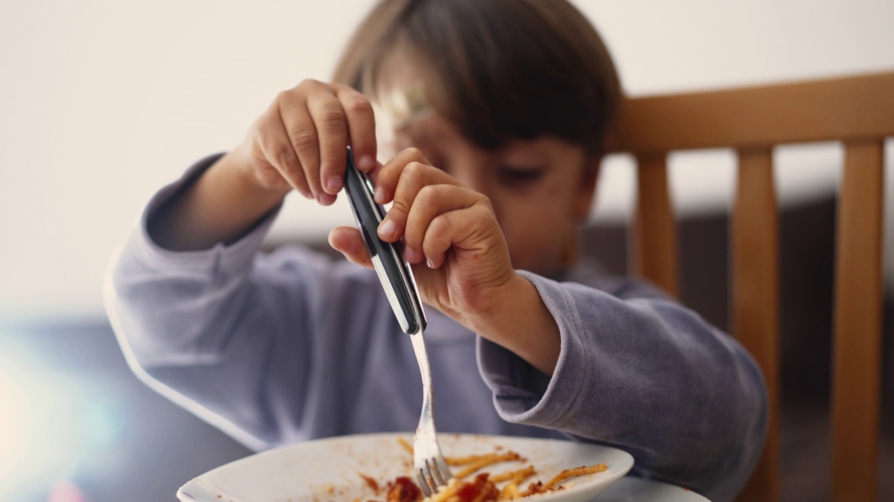 孩子用手和叉子旋转意大利面。孩子晚餐吃意大利面视频素材