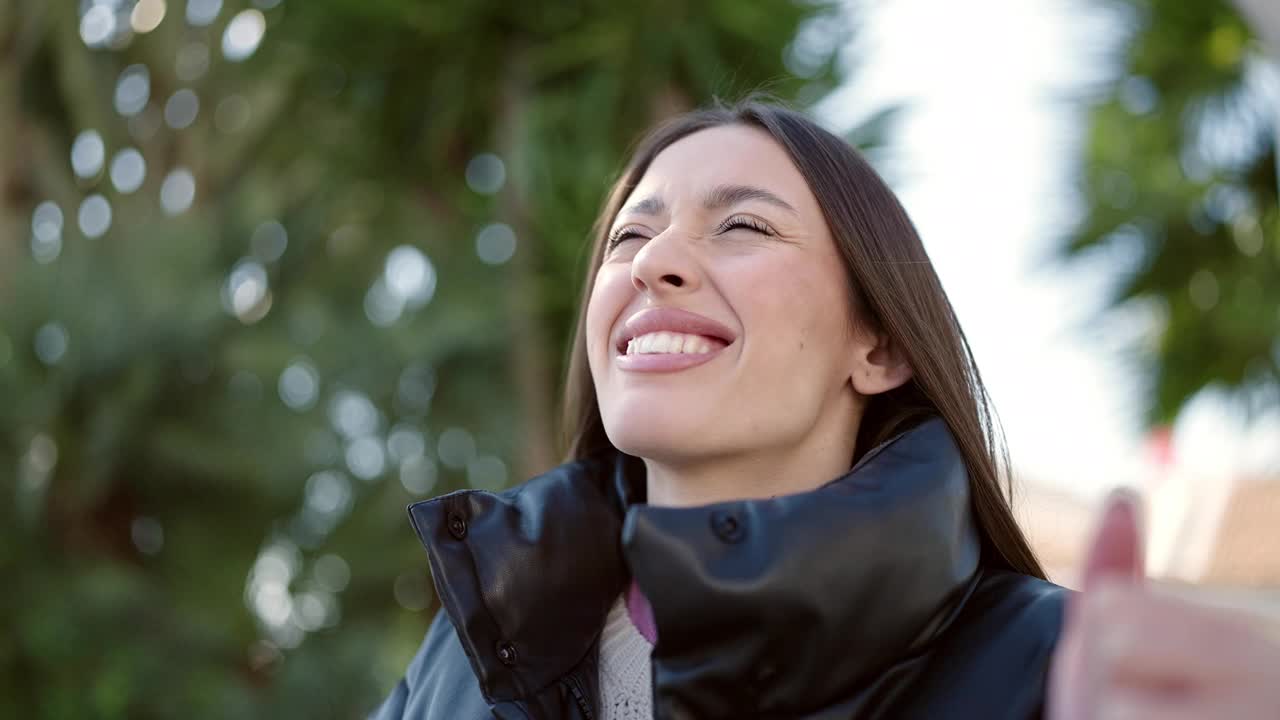 年轻美丽的西班牙女子站在公园与赢家的表情视频素材