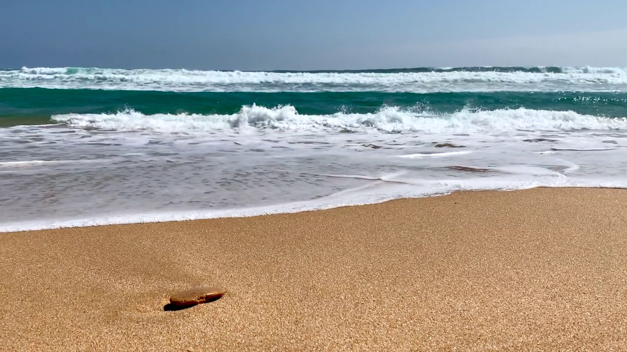 海浪拍打着有一块孤零零的石头的沙滩视频素材