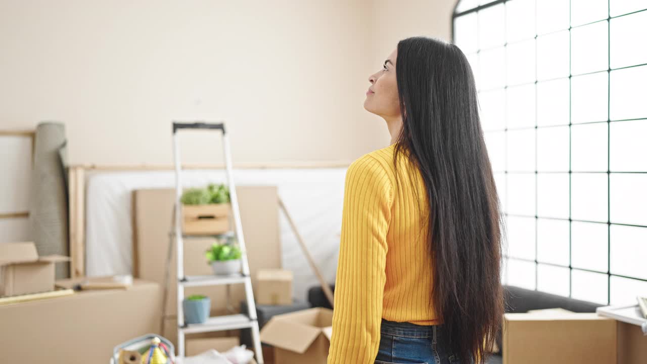 年轻美丽的西班牙女子站在新家的背影上视频素材