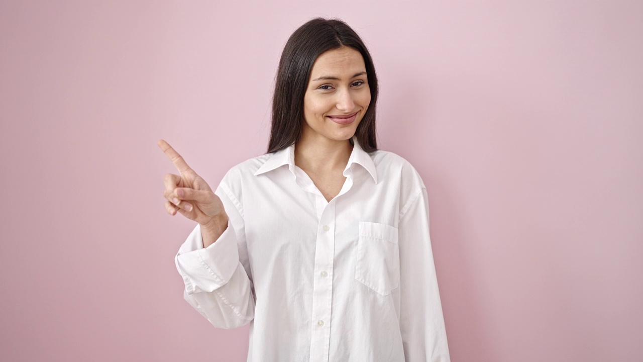 年轻美丽的西班牙女人指着自己说不，用手指在孤立的粉红色背景视频素材