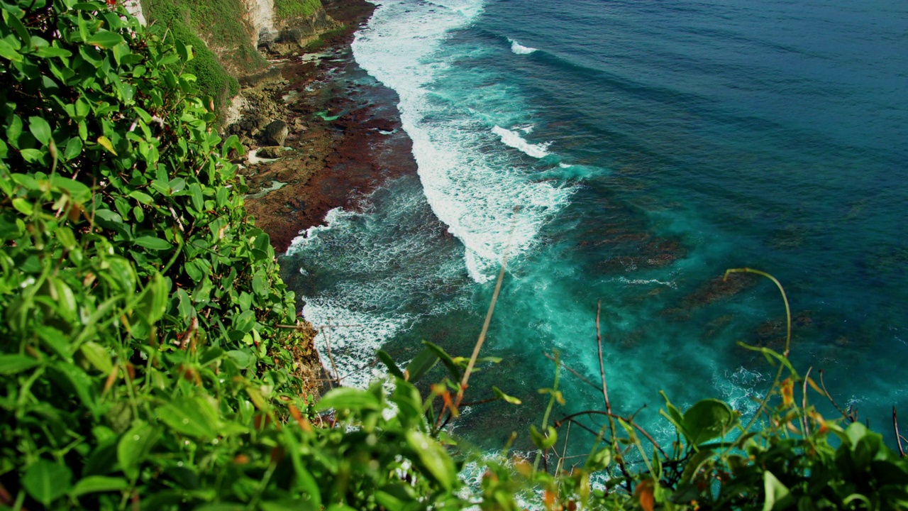 巴厘岛风景优美的原始绿色海滩，适合暑假度假。巴厘岛美丽的蓝色海水和多岩石的海岸线。Uluwatu。静态慢镜头。视频素材