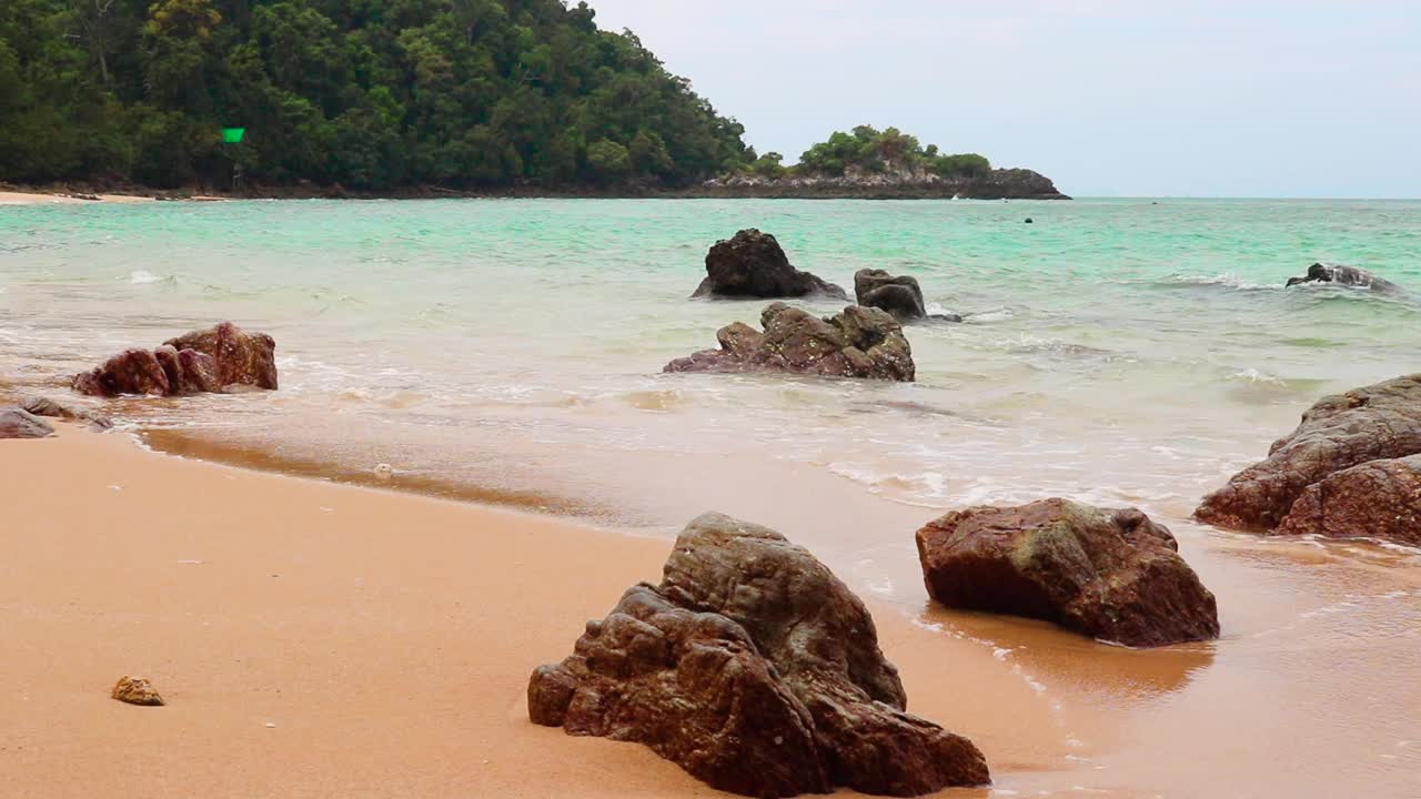 美丽蔚蓝的大海，浪花翻滚，海浪在沙滩上翻滚着石头视频素材