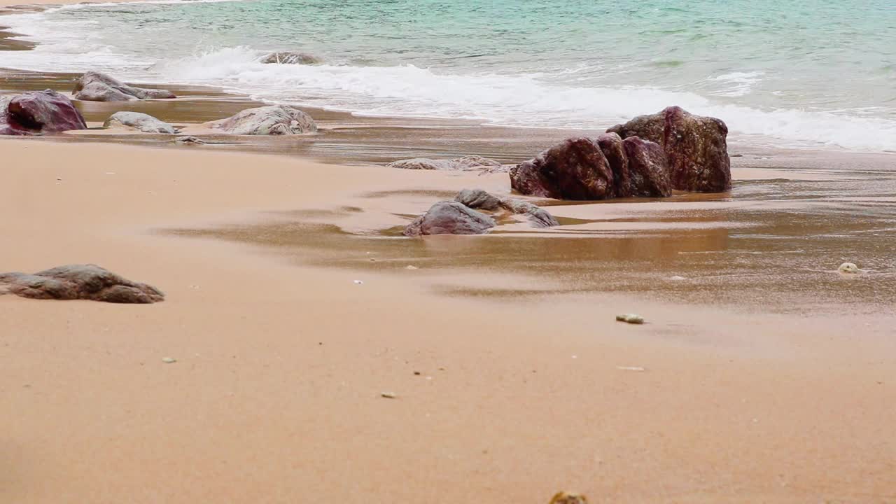 蔚蓝的大海，波涛汹涌，海浪在带着石头的沙滩上翻滚。视频素材