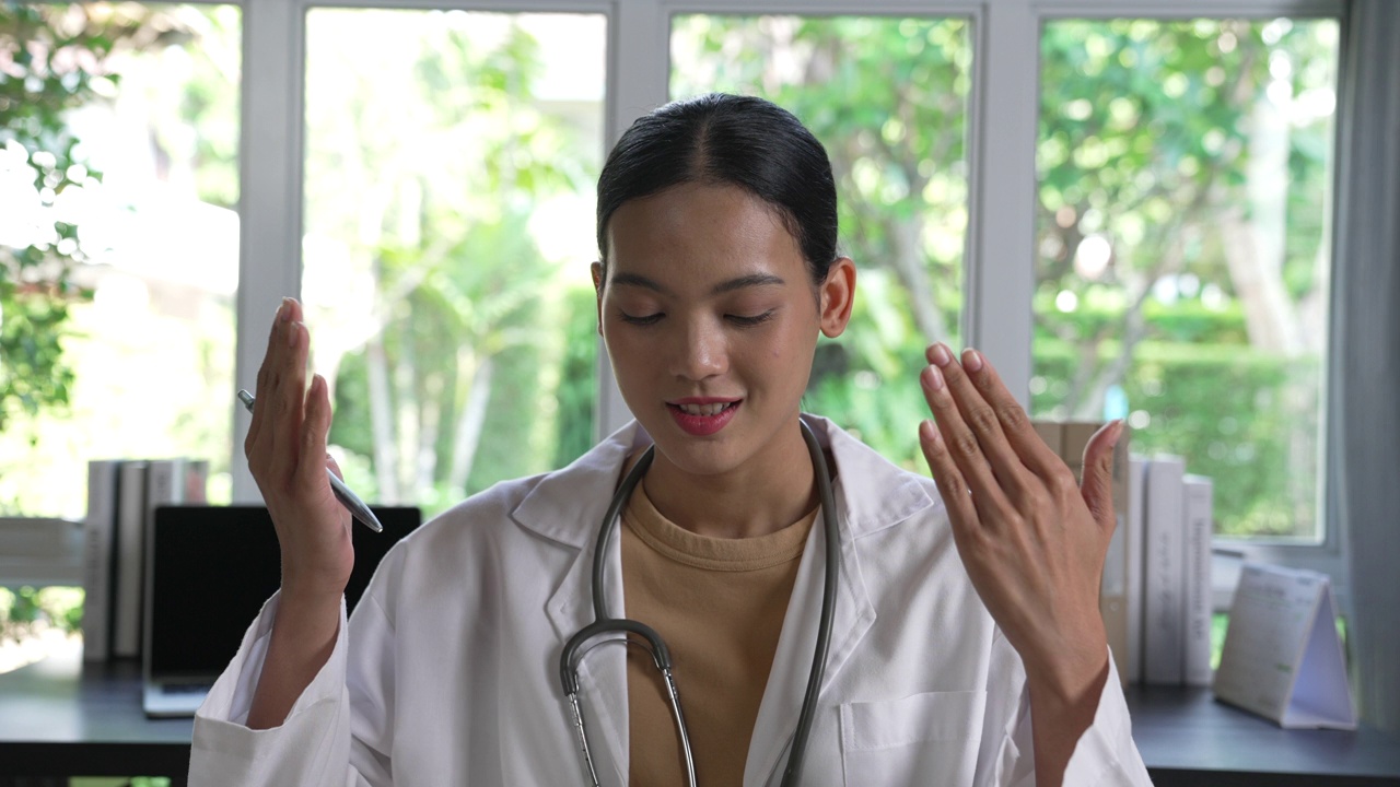 年轻的亚洲女医生与患者进行在线咨询。年轻的女医生进行视频通话视频素材