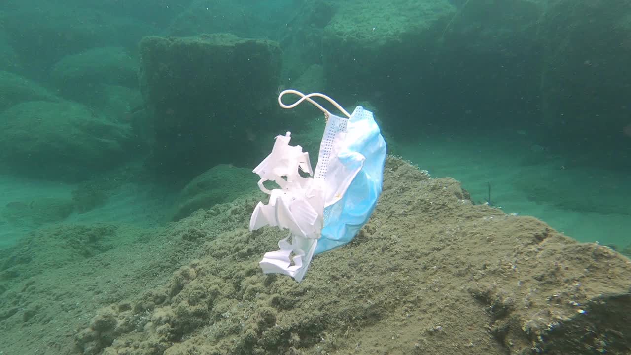 外科口罩和塑料杯漂浮在污染的海洋珊瑚礁生态系统视频下载