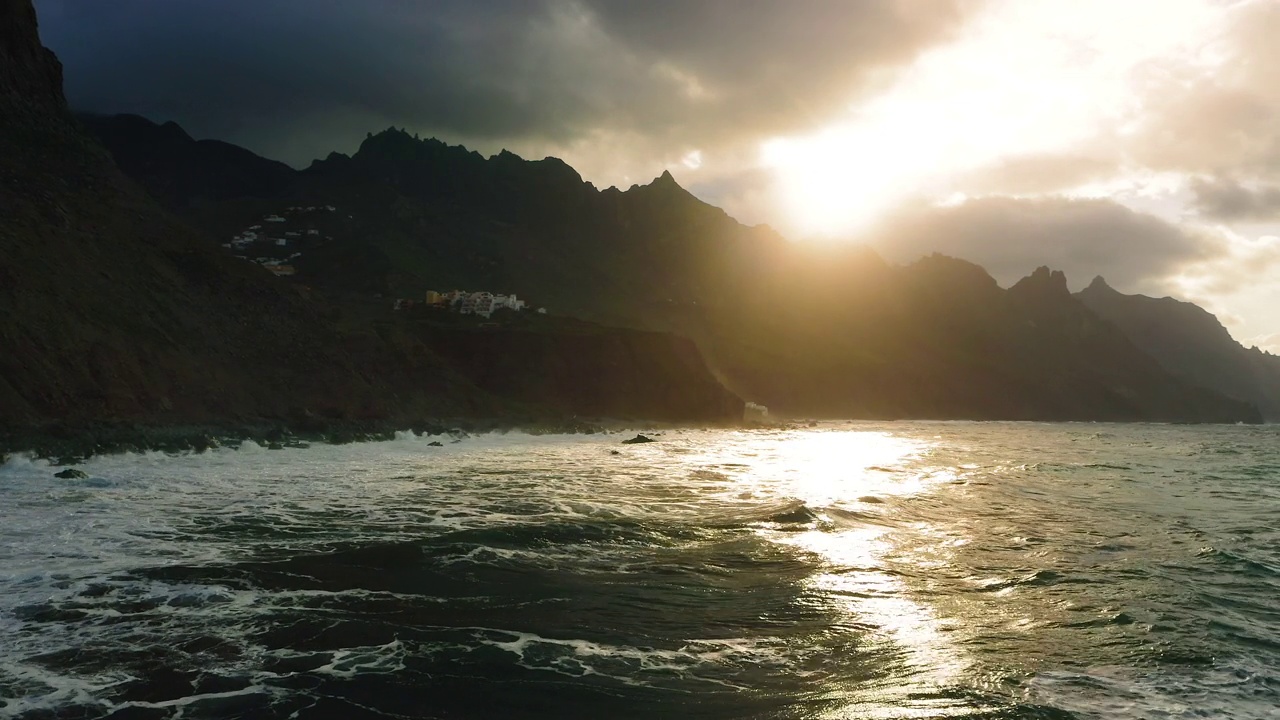 强大的海浪冲击着岩石火山海滩。日落在山的剪影。热带无人自然海景。天堂般的特内里费岛，金丝雀风景。无人机拍摄的画面。视频素材