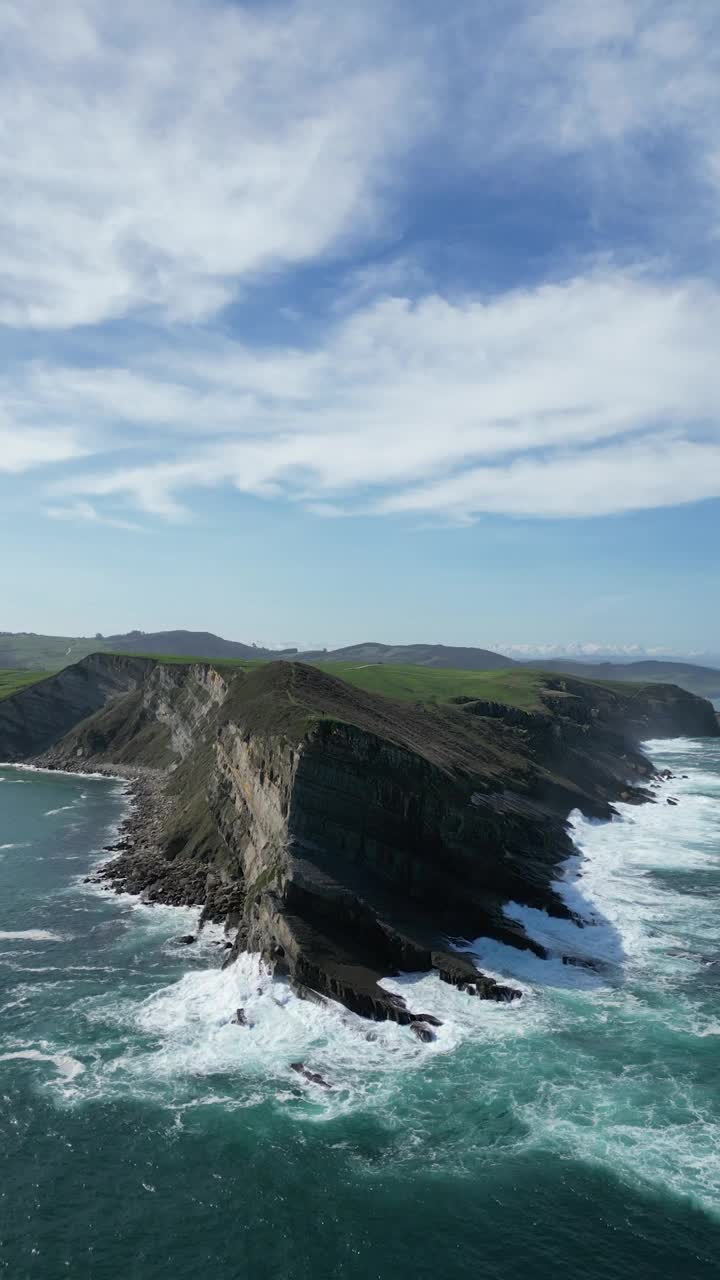 在阳光明媚的日子里，巨大的悬崖被泡沫般的海水包围着视频素材