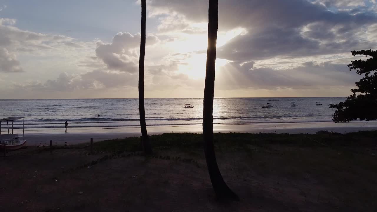 日落时分，无人驾驶飞机在海上观看海滩上的小船视频素材