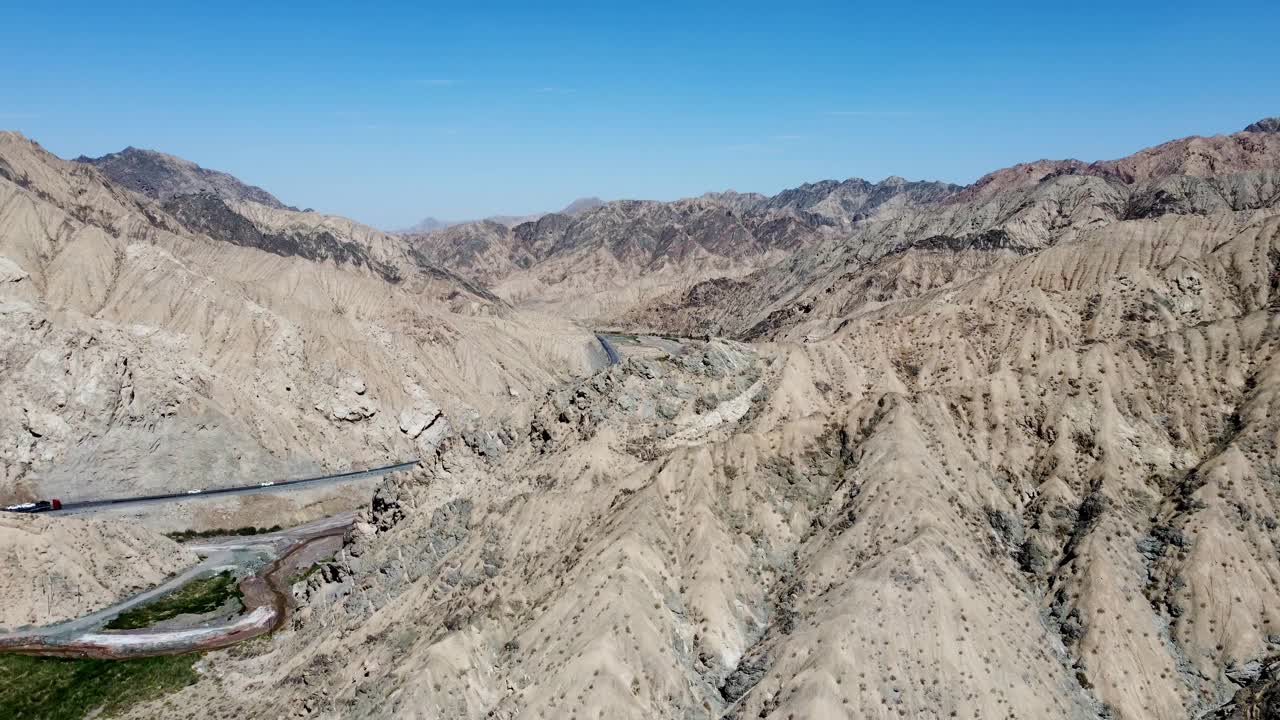 航拍视频显示汽车行驶在被干燥的沙漠岩石山脉包围的道路上视频素材